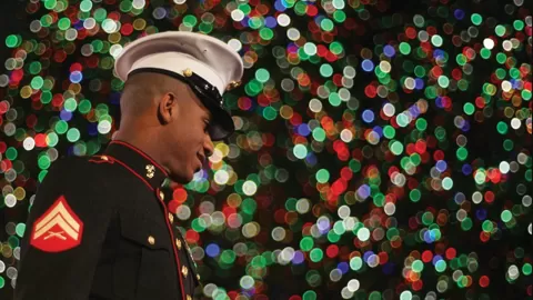 marine in front of holiday lights