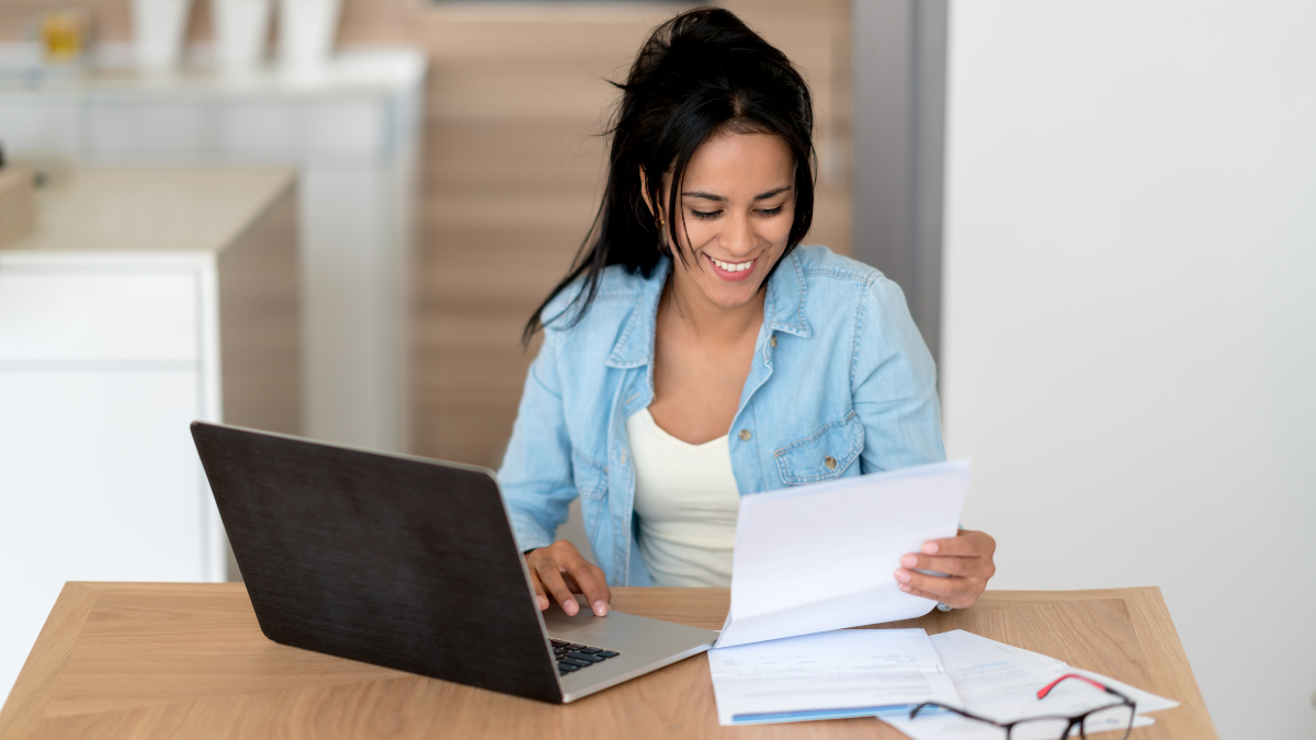 woman looking at paper and laptop