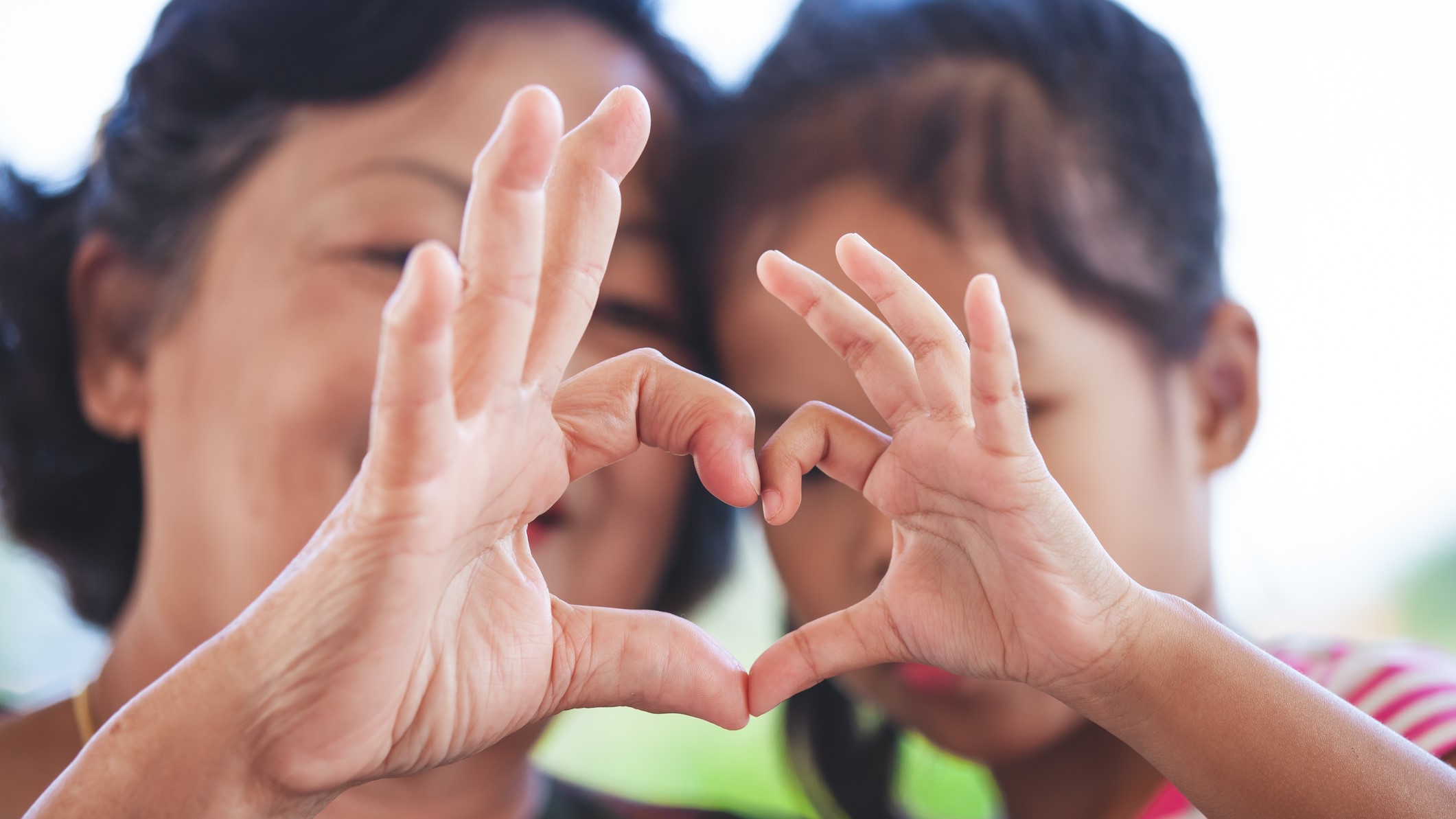 mom and daughter making heart symbol with hands