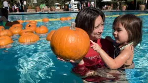 mother and daughter in a pool with a pumpkin