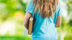 girl holding a book looking at her back