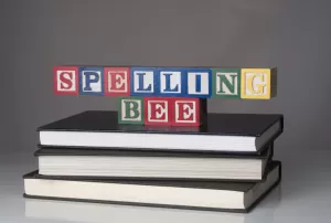 Letter blocks arranged to say "SPELLING BEE" stack atop books