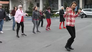 People line dancing in a parking lot.