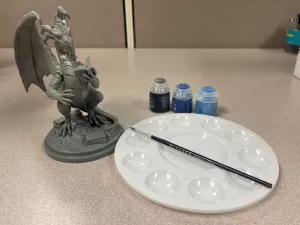 miniature painting setup with model, brushes, and paints