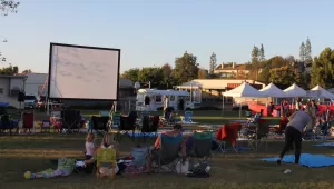 outdoor movie event with a crowd of people and children watching