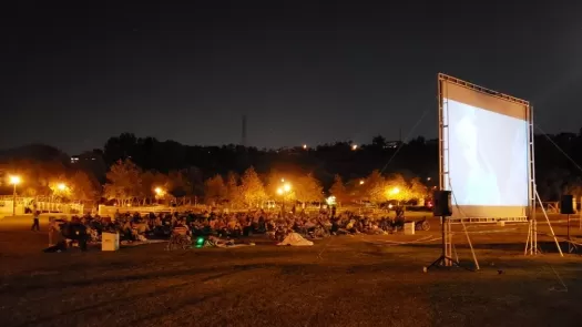 Outdoor movie playing in a park with a crowd watching