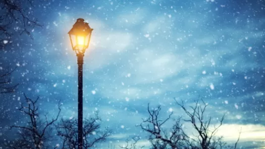 dark snowy night with a glowing lamppost