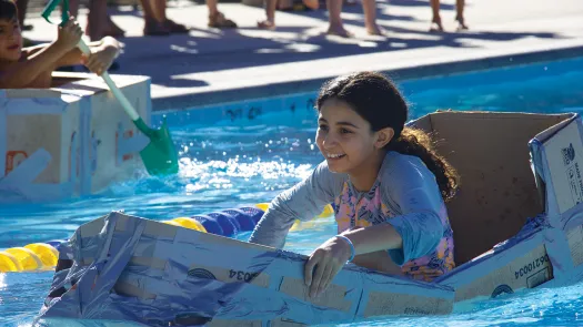 Cardboard Boat Derby participant riding in boat in pool