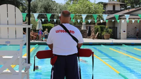 lifeguard standing on side of pool deck