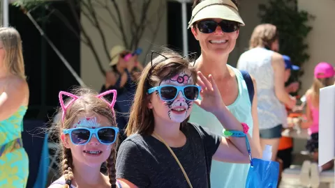 2 girls wearing face paint, cat ears and sunglasses with mom