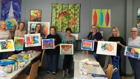 class of women holding up paintings