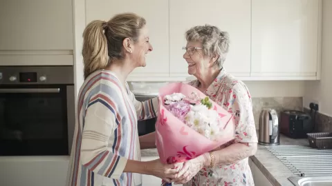 adult woman giving flowers to senior woman