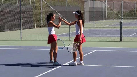 girls high-fiving on tennis court