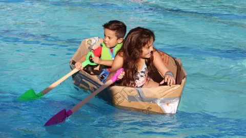 2 kids in cardboard boat in pool