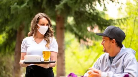 waitress wearing mask serving outside