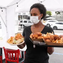 woman in mask serving food outside