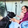 lady and baby sitting next to a dog