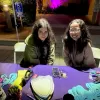 Two smiling teens working at mask decorating table