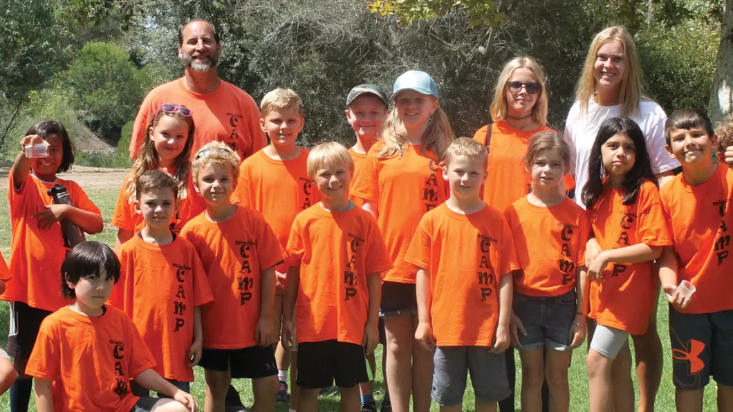 Group of summer camp kids and camp staff wearing orange Mission Camp Adventure t-shirts.