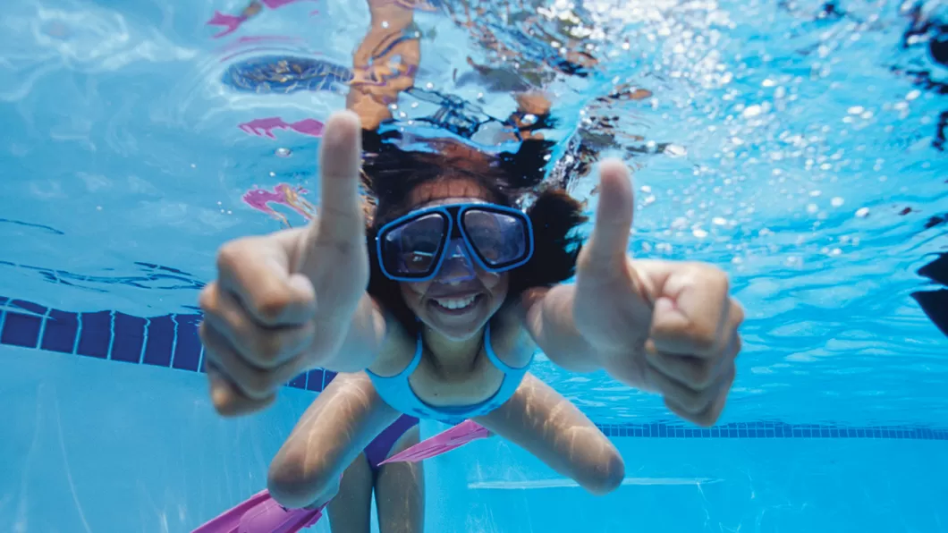 girl underwater swimming with her thumbs up